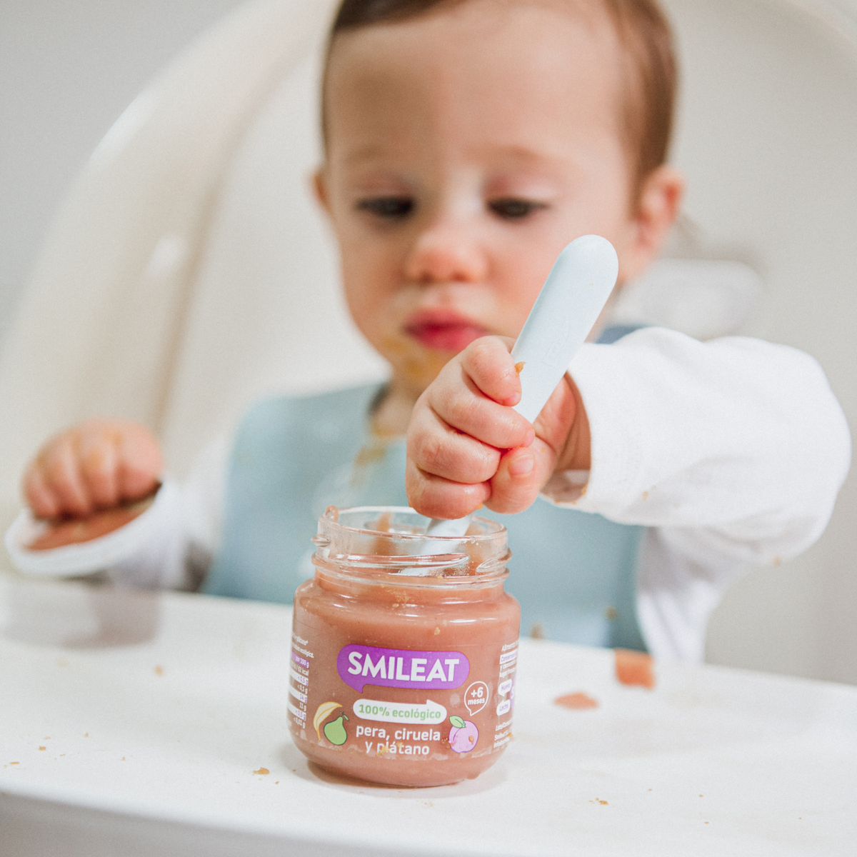 baby eating a little jar of pear, plum and banana